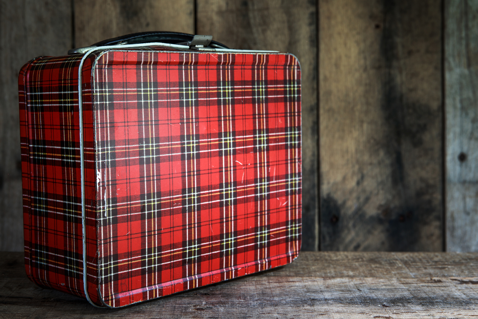 Vintage,Red,Metal,Lunchbox,On,A,Wooden,Background